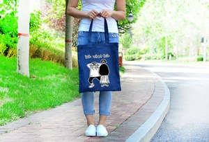 Dettaglio della borsa tote in tela blu navy con stampa di fumetti bianca e manici robusti