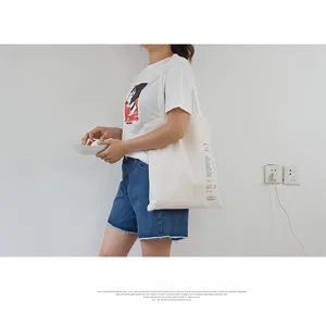 Detail of off-white canvas shoulder bag featuring black letter print and texture