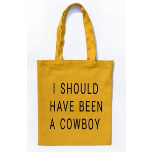 Detail of yellow canvas tote bag featuring bold black I SHOULD HAVE BEEN A COWBOY text