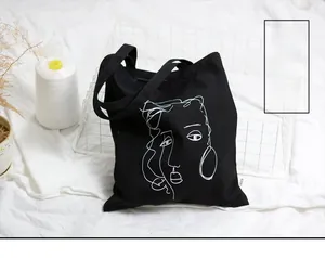 Détail d'un sac cabas en toile noire avec impression de portrait au trait blanc