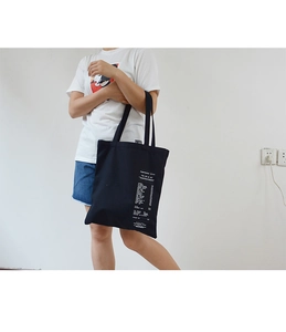 Detail of black canvas tote bag featuring minimalist white receipt style print graphics