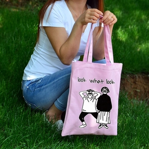 Dettaglio della borsa tote in tela rosa con design grafico e testo in un parco