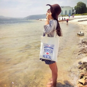 Minimalist white canvas tote bag with lettering, perfect for casual outdoor beach travel