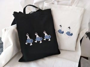 Detail of minimalist canvas tote bags in black and white with cute girl character print