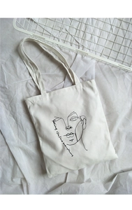 Detail of canvas tote bag with minimalist line art portrait and Seeing is everything text
