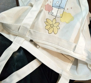 Detailed macro view of the zipper closure on this white canvas tote bag with floral print