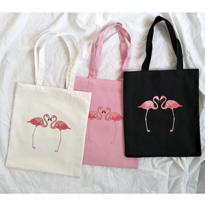 Detailed view of canvas tote bags with flamingo prints in white, pink and black