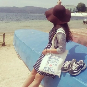 Minimalist white canvas tote bag with letter print shown in an outdoor beach setting