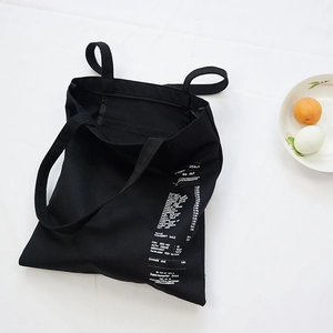 Black canvas tote bag with white receipt print featuring dual handles and shoulder straps