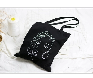 Gros plan du sac fourre-tout noir avec motif linéaire abstrait d'un visage blanc