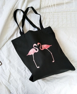 Detail of a black canvas tote bag featuring a cute pink flamingo print and sturdy handles