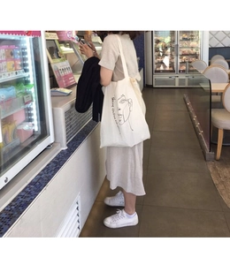 Detail of white canvas tote bag with minimalist face line art and quote text print