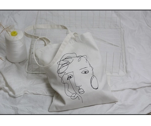 Détail du sac fourre-tout en toile crème avec portrait minimaliste abstrait noir