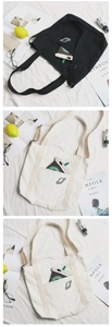 Dettaglio ricamo pianeta su borsa tote minimalista in tela con tasca frontale
