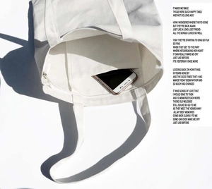 Detail showing white canvas tote bag interior with zipper closure and practical inner pocket
