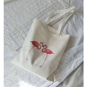 Detailed view of white canvas tote bag with symmetrical pink flamingo print and handles