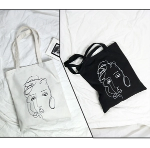 Gros plan sur l'imprimé abstrait de visages sur les sacs cabas en toile