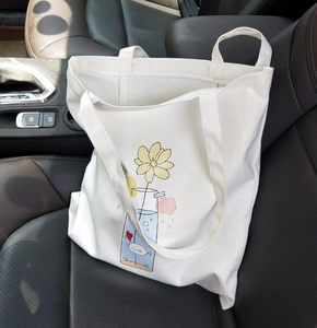 Detail of white canvas tote bag with floral fish illustration and zipper closure