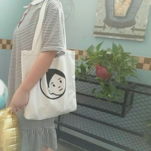 Close-up of minimalist white canvas tote bag with black cartoon face line art print