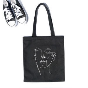 Minimalist black canvas tote bag with white line art portrait and twin handles