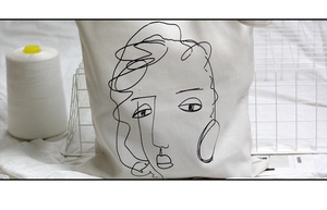 Détail du portrait abstrait minimaliste sur un sac cabas en toile blanche pour femme
