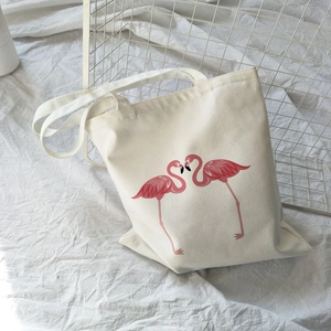 Detail of canvas tote bag featuring two pink flamingo prints on cream-white fabric