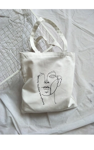 Detail of canvas tote bag featuring minimalist portrait line art and artistic text print
