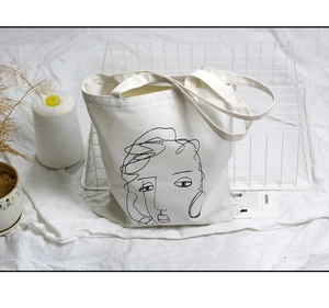 Détail d'un sac cabas en toile blanche avec art de ligne de visage abstrait et décor pur