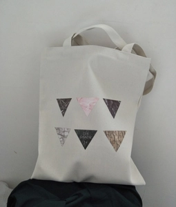 Detail of canvas tote bag with geometric triangle prints and artistic JIN SHAOW lettering