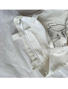 Close-up of cream canvas tote bag zipper closure and internal storage pocket detail