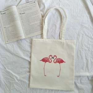 Detailed top view of off-white canvas tote bag featuring pink flamingo print design