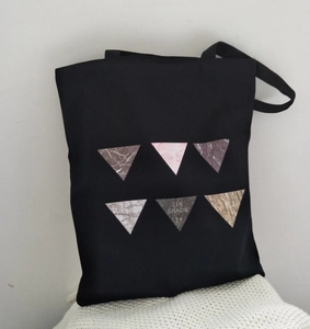 Detail of black canvas tote bag showing digital printed geometric triangle patterns