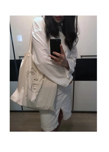 Close-up of minimalist cream canvas tote bag with artistic line art face print