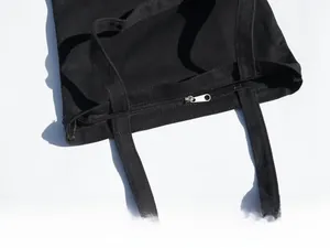 Detailed shot of smooth zipper closure and sturdy stitching on a black canvas tote bag