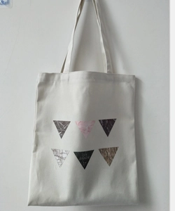 Close-up of beige canvas tote bag with geometric triangle patterns and sturdy shoulder straps