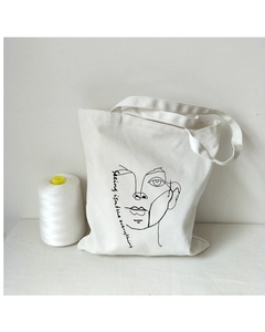 Detail of white canvas tote bag with minimalist face line art and quote print