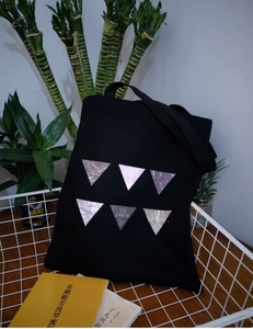 Detail of black canvas tote bag with marble triangle prints leaning on white basket