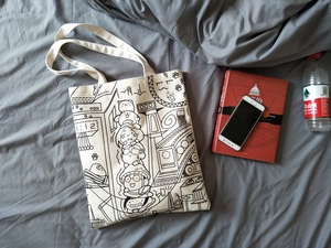 Detailed view of canvas tote bag featuring black and white cartoon comic illustrations
