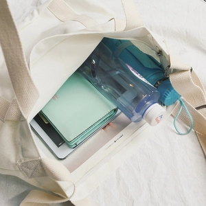 Grande borsa tote in tela bianca che mostra lo spazio interno per tablet e bottiglie
