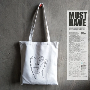 Minimalist canvas tote bag featuring an artistic line face print and shoulder straps