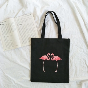 Minimalist black canvas tote bag featuring pink flamingo print on white fabric background