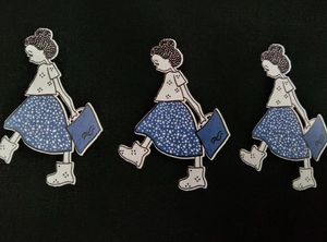 Three identical cartoon girl canvas stickers on a black textured fabric background