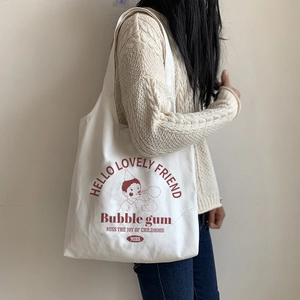 Detail of off-white canvas tote bag featuring a vintage red boy blowing bubbles illustration