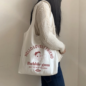 Detail of white canvas tote bag with vintage bubble gum boy print worn by a model