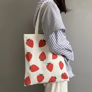 Detailed side view of large capacity white canvas tote with all-over strawberry print