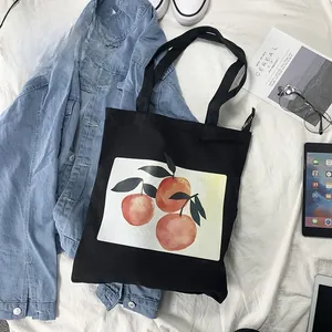 Detail of black canvas tote bag featuring a vibrant orange print in a flat lay setting