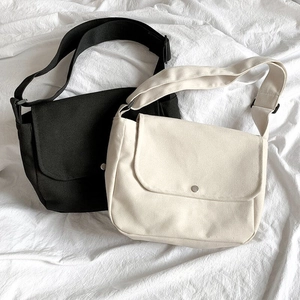 Detail view of canvas messenger bags in black and beige with adjustable shoulder straps