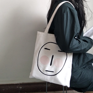 Borsa tote in tela bianca con stampa di faccina carina mostrata a tracolla dal modello