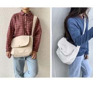 Detail of minimalist canvas crossbody bag with metal snap button and wide shoulder strap