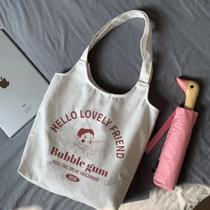 Close-up of a white canvas tote bag with a vintage boy blowing bubbles print detail